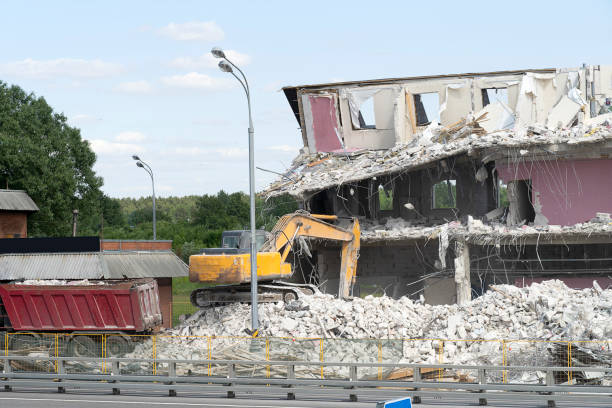 istock Yellow excavator picks up construction waste for loading onto a truck. Technique destroyed the building, is reinforcement, concrete and stones. Destroyed house, concrete, fittings. 1159223952
