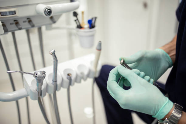 dentista en guantes de elección de pieza de mano para el procedimiento, equipo moderno en la clínica - handpiece fotografías e imágenes de stock