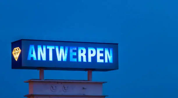 Photo of lighted blue neon light board with the text Antwerpen, Sign post illuminated by night in antwerp, Belgium