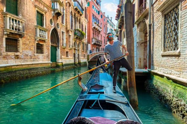 Gondolier with a paddle Handsome gondolier during gondola ride on the street of Venice, Italy gondolier stock pictures, royalty-free photos & images