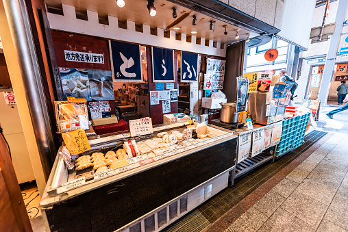 Kyoto, Japan - April 17, 2019: City with Nishiki market shops restaurants and tofu food vendor with nobody and sign for yuba skin
