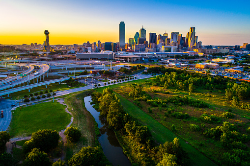 Aerial drone view River and green space above Dallas Texas Skyline Cityscape 2019 over green spaces , trees , sun beams , and bridge and highways