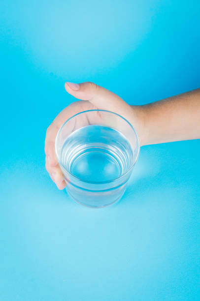 istock glass of water in hand on blue 1159236529