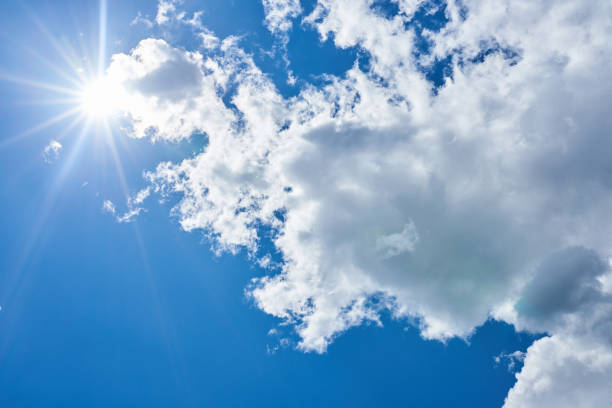 Blue sky with beautiful, gray-white, clouds and brightly shining sun stock photo
