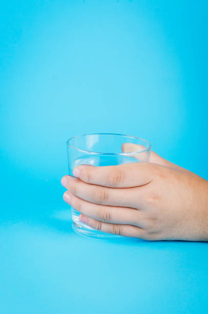 istock glass of water in hand on blue 1159236698