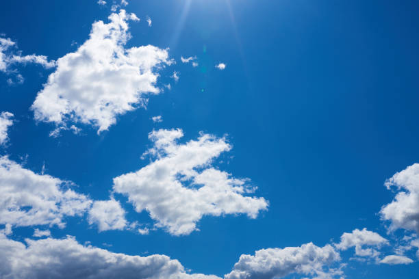 Blue sky with beautiful, grey-white, clouds and glare falling from the sun for any purpose
