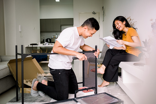 Young Couple Helping Each Other Assembling Table