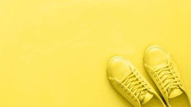 istock yellow sneakers on yellow background, copy space 1159239838