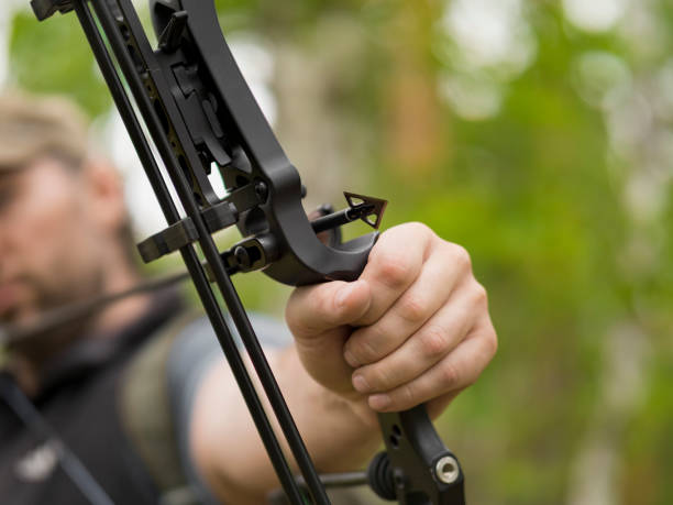 istock Man hunts in the forest with a bow. The hunter aims. Focus on sharp arrowhead 1159239924