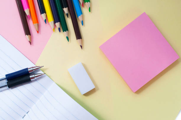 istock Notebook and colored pencils on a pink-yellow background 1159247578