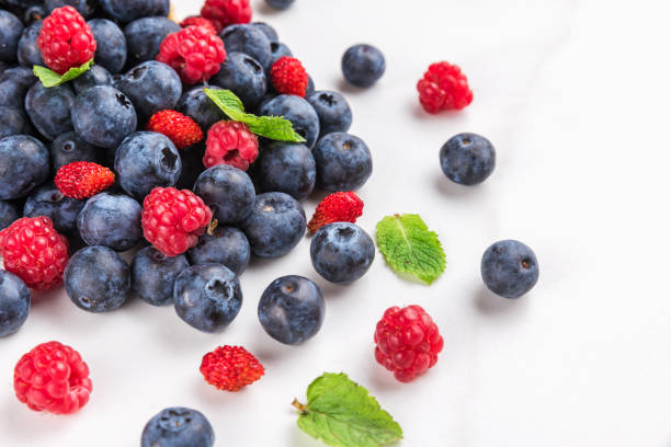 istock wild berries blueberry, strawberry and raspberry with mint on white marble background. summer food concept 1159249221