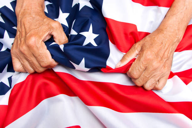 istock Elderly man hands compresses a USA flag. 1159250906
