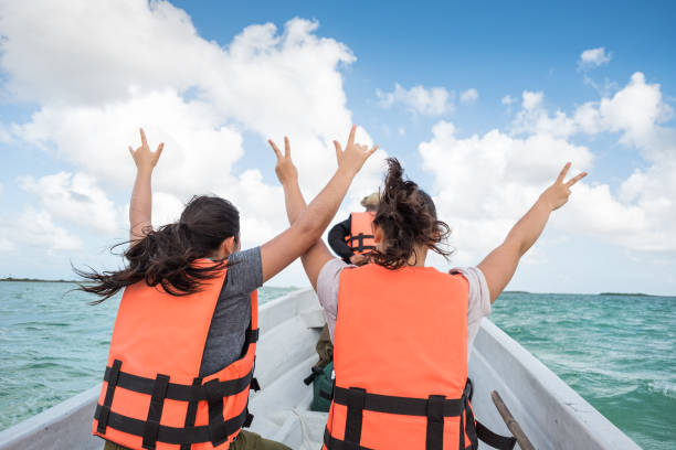 Multi-Ethnic Sisters on Boat Tour Raising Arms in Wind, Mexico Adventure and eco-tour guide and tourists in motor boat  entering open ocean.  Sian Ka-an Biosphere Reserve.  Tulum, Quintana Roo, Yucatan Peninsula, Mexico. family motorboat stock pictures, royalty-free photos & images