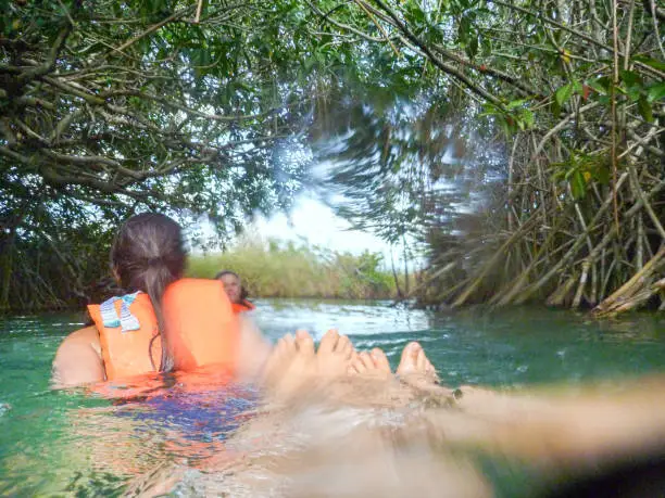 Adventure eco-touring.  POV of multi-ethnic tourist family swimming and floating down mangrove river channel.  Sian Ka-an Biosphere Reserve.  Tulum, Quintana Roo, Yucatan Peninsula, Mexico.