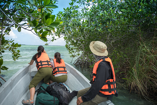 Adventure and eco-tour guide and tourists in motor boat exiting mangrove river channel and entering open ocean.  Sian Ka-an Biosphere Reserve.  Tulum, Quintana Roo, Yucatan Peninsula, Mexico.