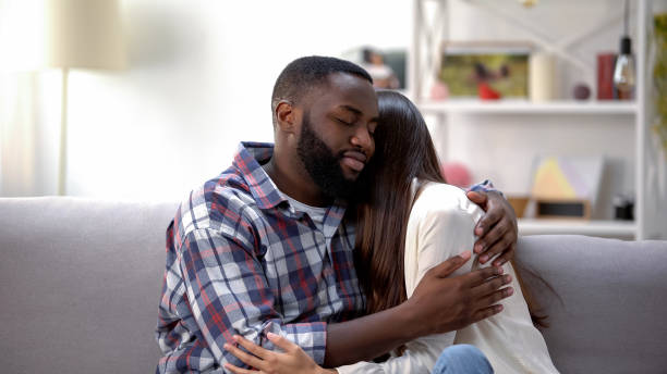istock Happy multiethnic couple cuddling on sofa at home, making peace after quarrel 1159251319