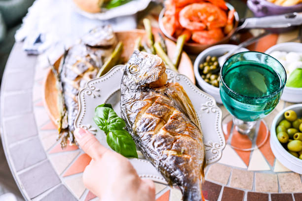 istock Fried fish on a plate. Dining table with different food and snacks. Seafood and vegetables. Summer lunch in the open air. 1159252211