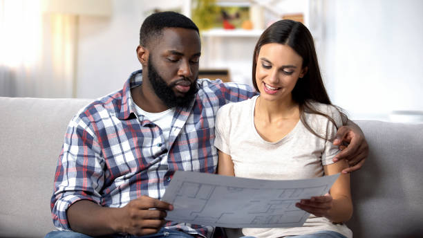 istock Young multiracial family looking at building plan, choosing interior design 1159252246