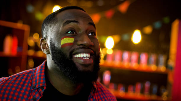 istock Extremely happy black spanish fan with flag on cheek shouting, team winning 1159252556