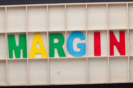 The word Margin spelled with colorful alphabet letters on wooden surface.