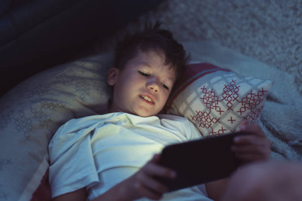 istock Little boy playing on tablet at night in bedroom 1159270029
