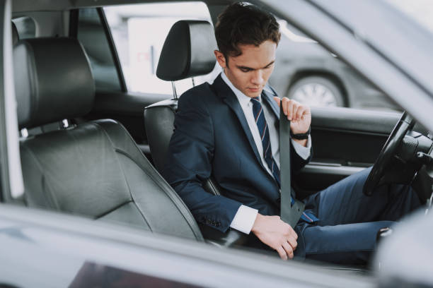 istock Young man in black suit using seat belt in his auto 1159270184