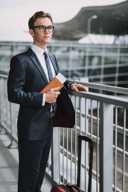 istock Young businessman is waiting for flight with suitcase 1159270255