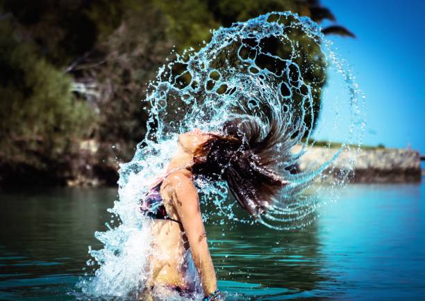 Woman standing in a lagoon, flicking hair back stock photo