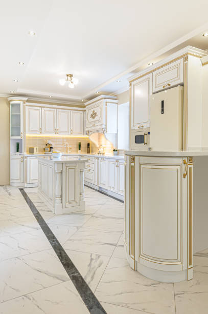 interior of neoclassical style white and gold wooden kitchen with island in luxury home