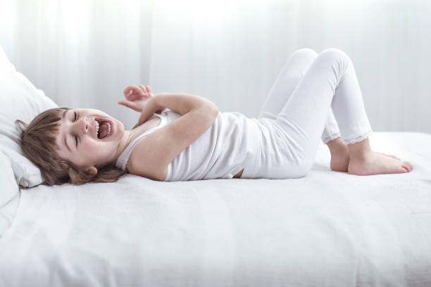 istock Cute little girl smiling while lying in a cozy white bed 1159272289
