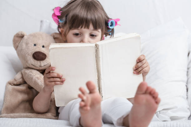 istock Cute little girl smiling while lying in a cozy white bed 1159272295