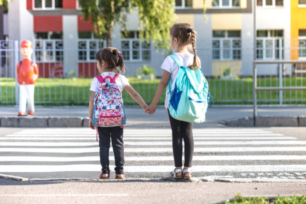Back to school education concept with girl kids, elementary students, carrying backpacks going to class
