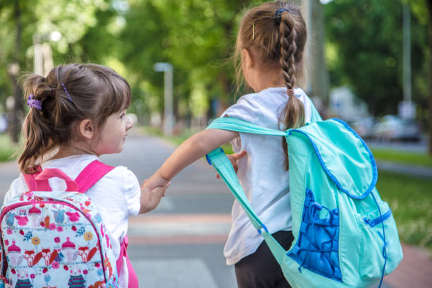 istock Back to school education concept with girl kids, elementary students, carrying backpacks going to class 1159273197