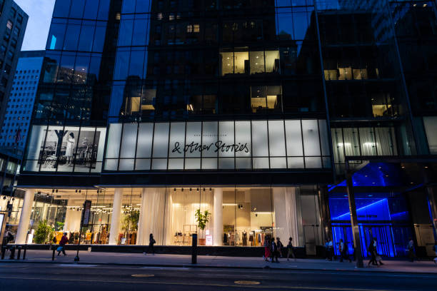 Luxury clothing store in New York City, USA New York City, USA - August 1, 2018: Display of a luxury clothing store at night with people around in Fifth Avenue (5th Avenue), Manhattan, New York City, USA window shopping at night stock pictures, royalty-free photos & images