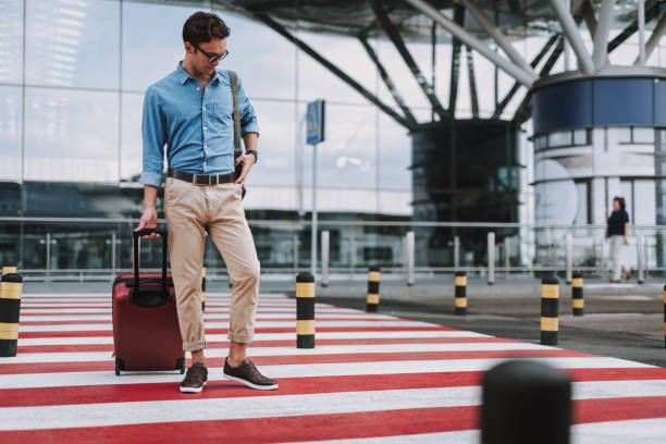 istock Young guy with suitcase walking on crosswalk outdoors 1159274453