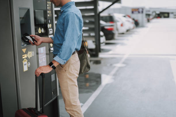 istock Young guy making payment with mobile phone in the parking 1159274480