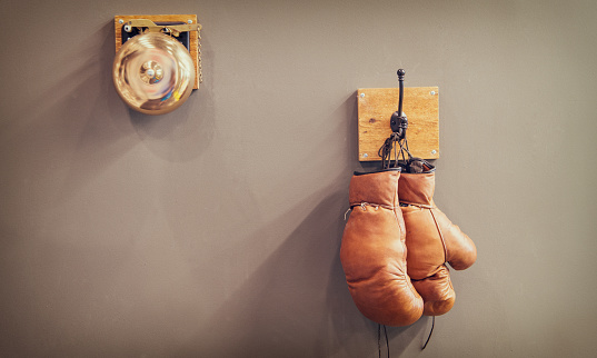 history of sport. vintage gong and worn gloves. stamina. final gong in battle retro boxing gloves. vintage sport equipment. boxing concept. old boxing gloves on hanger. copy space. Final sparring.
