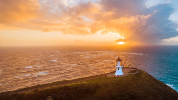 Two distant figures walking towards the famous lighthouse at the northern tip of New Zealand, the point where the Tasman Sea meats the Pacific Ocean.