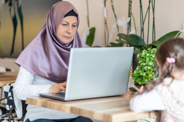 istock Muslim mom working while her  daughter lingers on cell phone 1159282498