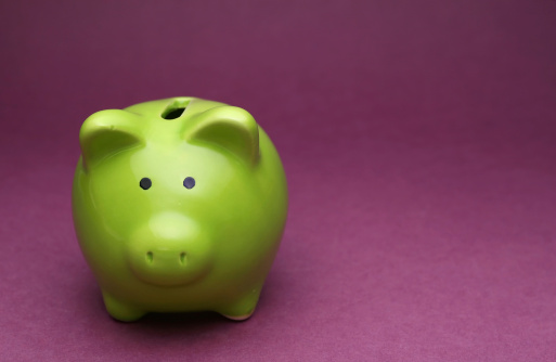 A green piggy bank on purple background, shot from the front
