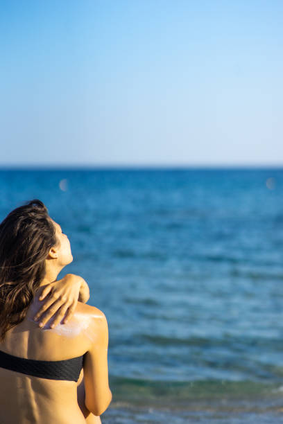 istock young woman applying sun cream to her back 1159286709