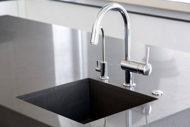 istock kitchen sink of dark gray stone with chrome faucet in a clean kitchen with a glossy work surface, close up faucet sink. 1159287989