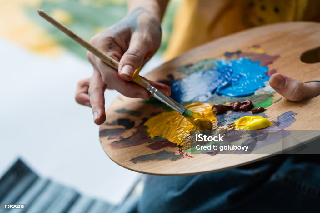 fine art school artist mix acrylic paint palette Fine art school. Closeup of artist hands holding wooden palette, mixing acrylic paint with brush. Artist Stock Photo