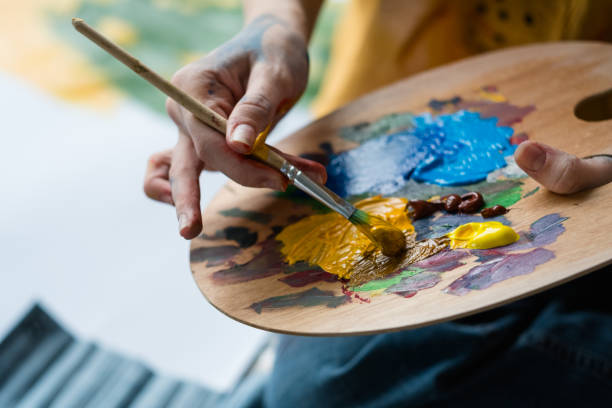 fine art school artist mix acrylic paint palette Fine art school. Closeup of artist hands holding wooden palette, mixing acrylic paint with brush. acrylic painting stock pictures, royalty-free photos & images