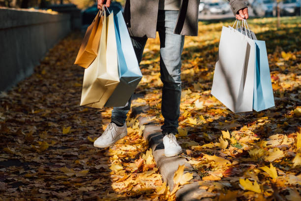 istock autumn fun man shopping bags fall leaves sidewalk 1159292287