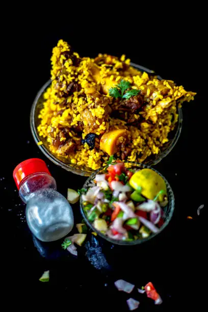 Popular Indian & Asian kashmiri dish i.e. yakhni or akhni in a glass plate along with some salad and salt on black colored shiny surface.