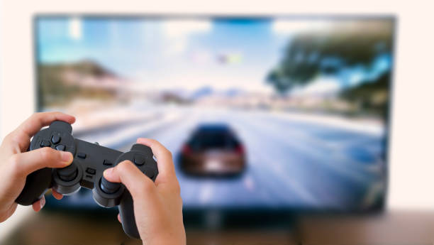 The boy play with computer and consol racing game. boy holds in his hand the game console.