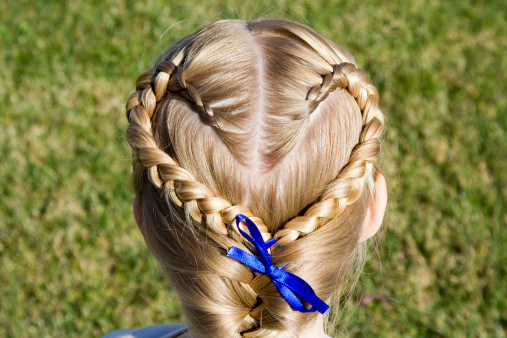 Young girl shows off her hair braided into a heart shape.
