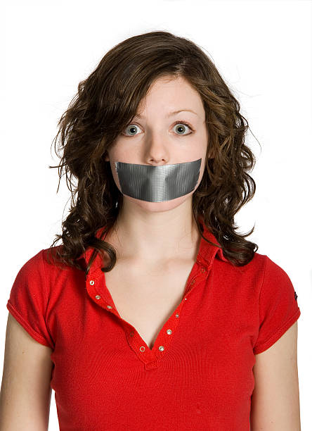 Teenage Girl with Mouth Taped Closed on White Background stock photo