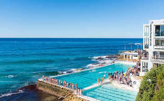 Sydney, Australia - June 30 2019: Swimmers compete in a relay at the world famous Bondi Icebergs swimming pool on a sunny winter's day.